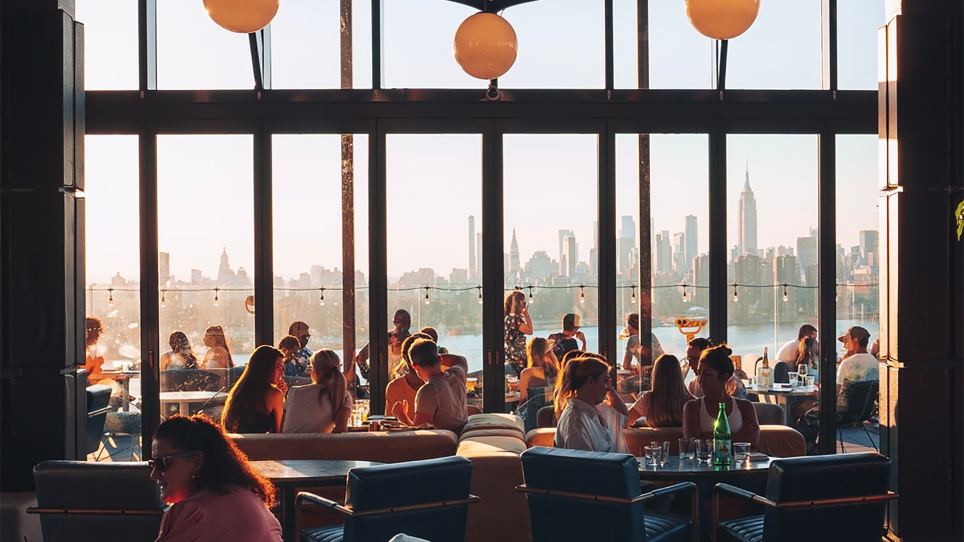 people in a bar with a view of the city at the back